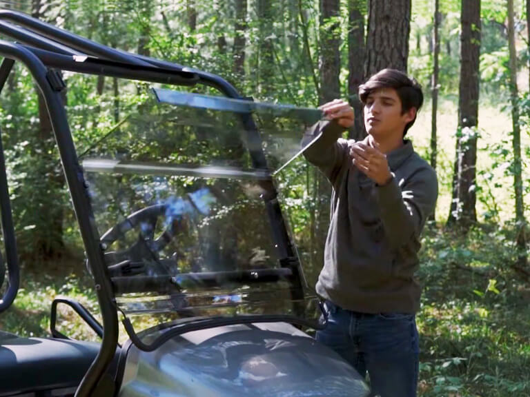 man folding down golf cart windshield