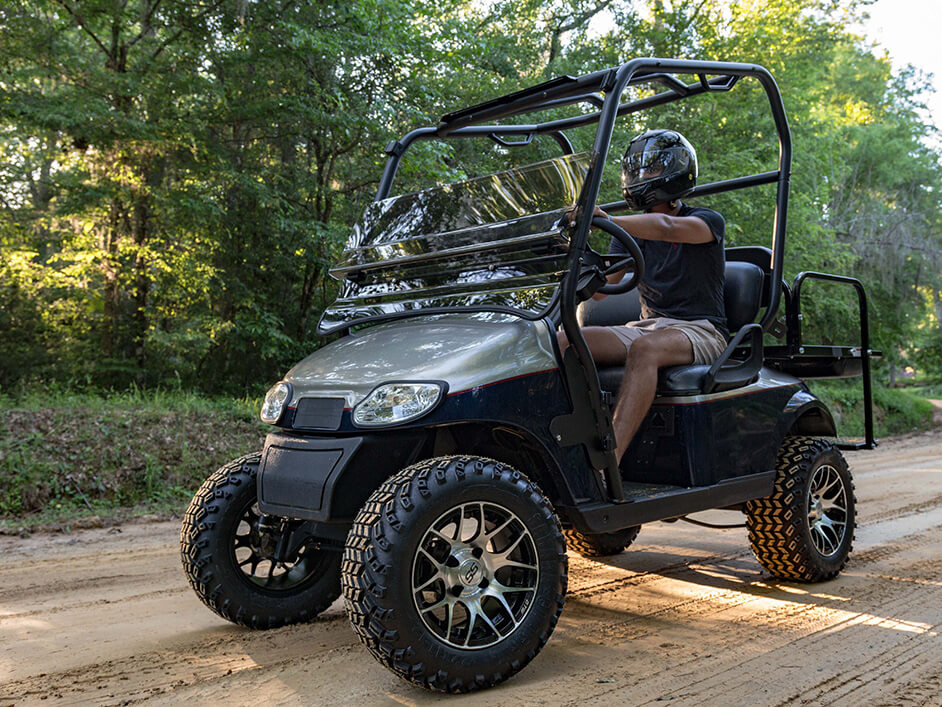golf cart on dirt road with driver wearing a helmet