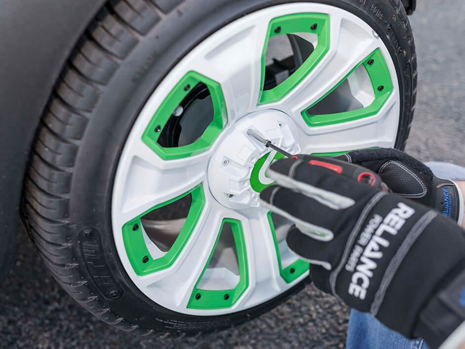 gloved hands screwing a golf cart tire on