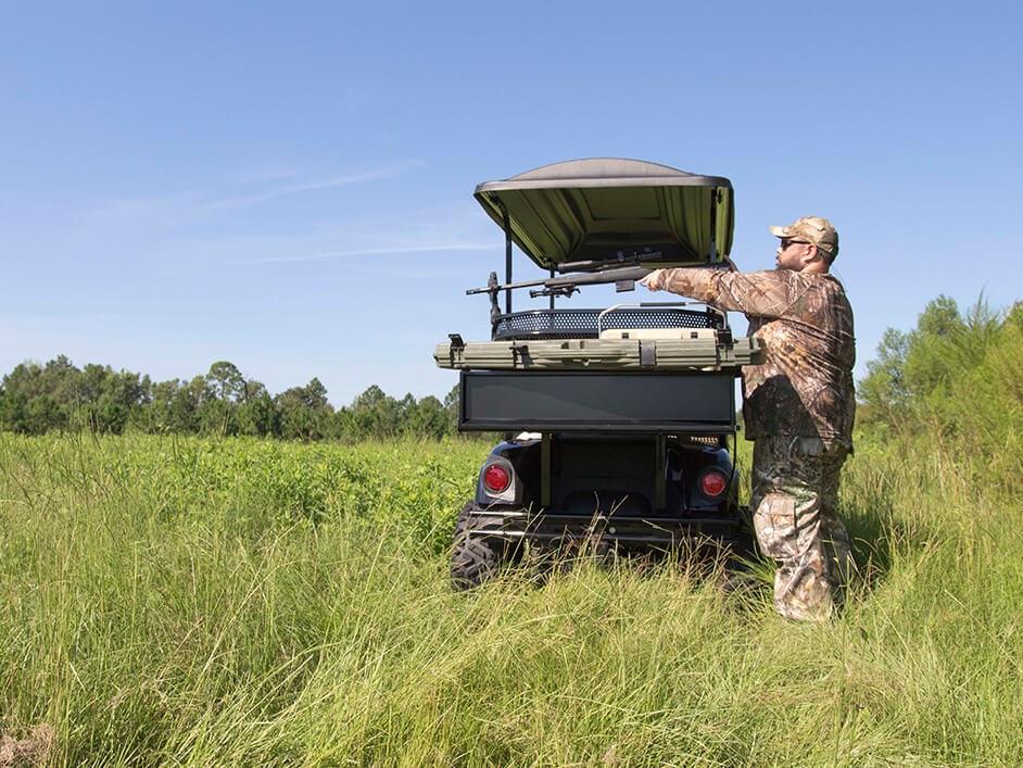 man putting gun into gun rack on golf cart